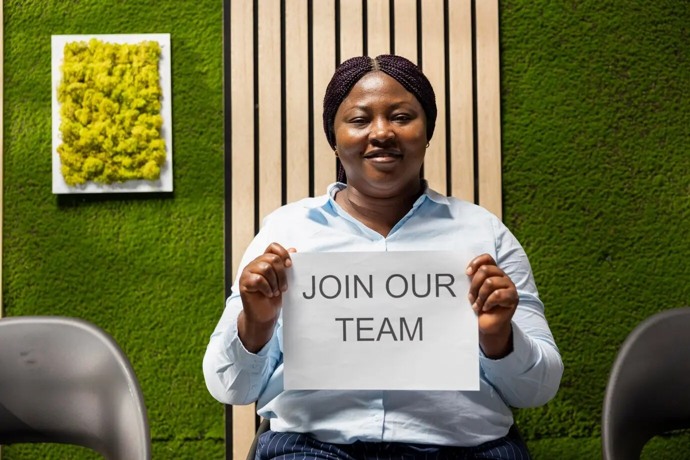 An African American human resources manager holds an office advertisement inviting applicants.